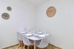 a table with chairs and a clock on the wall at LE LOGY-COSY - Appartement 5 pers - Clim Wifi Cosy Garage in Saint-Gilles