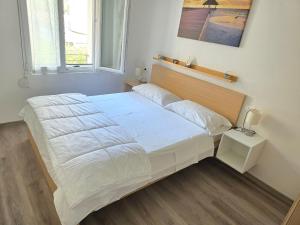 1 dormitorio con 1 cama grande con sábanas blancas en Villa Nerina Apartment, en Lignano Sabbiadoro