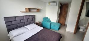 a bedroom with a bed and a blue chair at Rodadero- Ámbar Deluxe in Santa Marta +15 photos