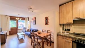 a kitchen and living room with a table and a blue couch at Aprtamento El Llagu Zolitru in Llanes