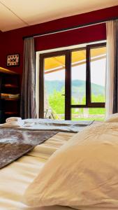 a bedroom with a bed and a large window at Hotel Hobbiton near Vardzia Caves in T'mogvi