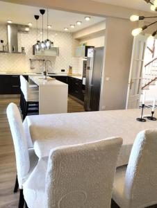 a kitchen with a table with white chairs and a kitchen with a counter at Vivienda familiar cerca de Toledo y de Puy Du Fou in Burguillos de Toledo