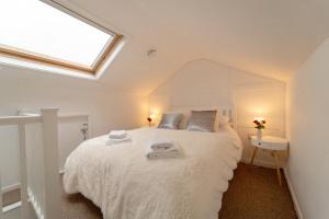 um quarto com uma grande cama branca e uma clarabóia em Kirkmoor Cottage - Cosy home central Clitheroe em Clitheroe