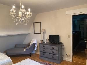een slaapkamer met een stoel en een televisie op een dressoir bij le jardin adele in Drucat