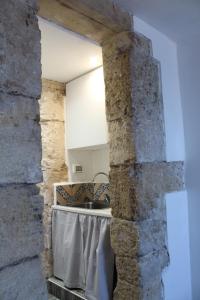 a kitchen with a stone wall and a sink at Brezza Marina Ortigia in Siracusa