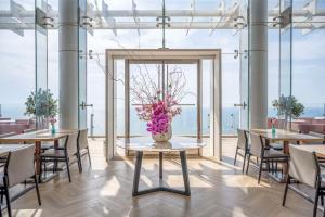 una sala da pranzo con tavoli, sedie e un vaso di fiori di The David Kempinski Tel Aviv a Tel Aviv