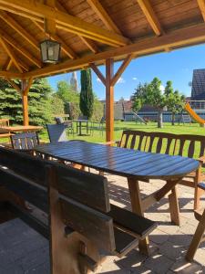 Una mesa de picnic de madera con bancos bajo un techo de madera. en Ferienwohnungen Zeller, en Wolframs-Eschenbach