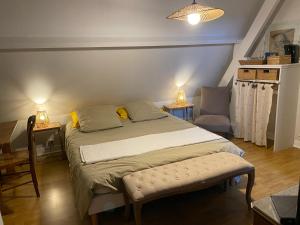 a bedroom with a large bed and a chair at le jardin adele in Drucat
