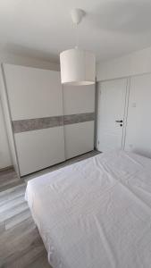 een witte slaapkamer met een groot bed en een kroonluchter bij Apartments Borić in Cres