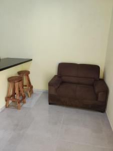 uma sala de estar com um sofá castanho e dois bancos em Casa Amarela em São Miguel dos Milagres