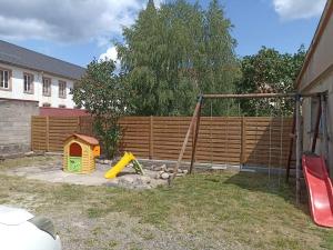 einen Hinterhof mit einem Zaun und einem Spielset in der Unterkunft Gîte Les 3 Cerfs - 3 étoiles in Plainfaing