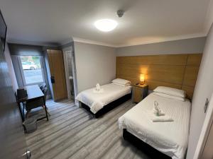 a hotel room with two beds and a desk and a lamp at Auld Mill House Hotel in Dunfermline