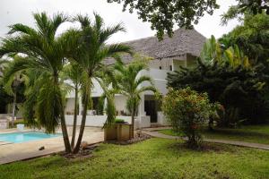 une villa avec une piscine et des palmiers dans l'établissement Galu Backpackers & Ecolodge, à Diani Beach