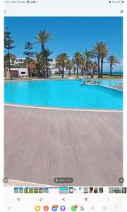 a large blue swimming pool with palm trees in the background at Fantástic apartment the beach marina 2 in Tetouan