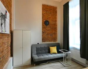 a living room with a gray couch and a brick wall at Hola Apartamenty Legionow 2 in Łódź