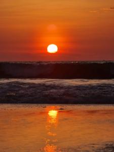 una puesta de sol en una playa con olas y el océano en Hotel Ola Bella, en San Clemente
