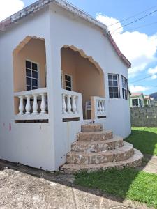 una casa blanca con escaleras delante en Cozy 2BR/1BA retreat in St.Kitts close to airport, en Romneys