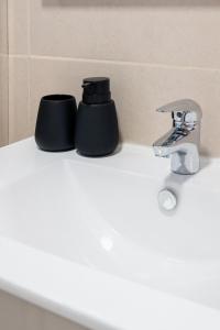 a bathroom sink with two black cups on it at Caniçada House - Gerês in Vieira do Minho +26 photos