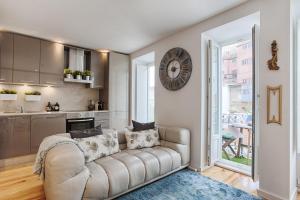 a living room with a couch and a clock on the wall at BmyGuest - 28 Tram Central Apartment in Lisbon