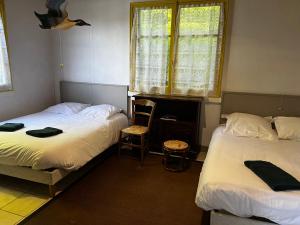 a bedroom with two beds and a window and a chair at Chalet au bord de l'étang 4 pers in Les Boulmiers