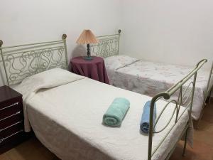 two beds in a bedroom with a lamp on a table at A casa da Maria in Luz de Tavira