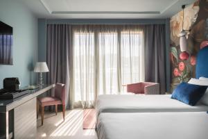 a hotel room with a bed and a desk and a window at Hotel Antik San Sebastián in Donostia-San Sebastián