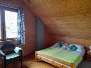 1 dormitorio con 1 cama y 1 silla en una cabaña en Holiday homes for 7 people in winouj cie, en Karsibór