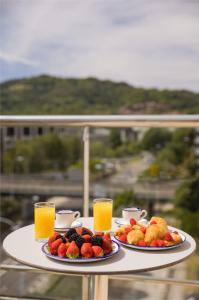 two plates of fruit and orange juice on a table at Hotel Antik San Sebastián in Donostia-San Sebastián