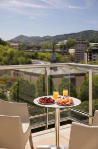 una mesa con 2 platos de fruta en el balcón en Hotel Antik San Sebastián, en San Sebastián