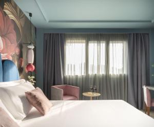 a bedroom with a bed and a chair and a window at Hotel Antik San Sebastián in Donostia-San Sebastián