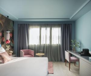 a bedroom with a large bed and a desk and chairs at Hotel Antik San Sebastián in Donostia-San Sebastián