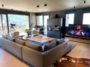 a living room with a large couch and a fireplace at Luxury Ski Chalet Andorra in Soldeu