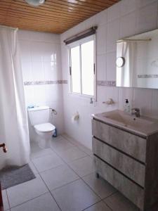 uma casa de banho com um lavatório, um WC e uma janela. em Casa-Molino em Tuineje