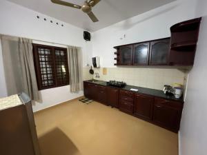 a kitchen with wooden cabinets and a ceiling fan at Mangosteen villa in Cochin