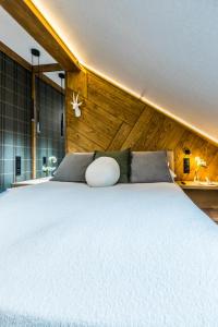 a bedroom with a white bed with a wooden wall at Apartamenty ForRest Krupówki in Zakopane
