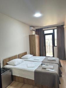 dwa łóżka w pokoju z oknem w obiekcie Dalida Hotel w mieście Tbilisi City