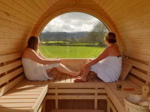 duas mulheres sentadas numa sauna a olhar pela janela em Aspen Leaves: The perfect farm retreat em Graffham