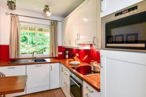 a kitchen with white cabinets and red walls at Litzkow 16101 in Archsum
