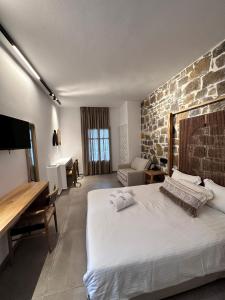 1 dormitorio con 1 cama grande y pared de piedra en Aelia Studios en Aegiali
