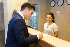 Un uomo che firma un documento con una donna dietro una scrivania di Fesa Business Hotel a Gebze