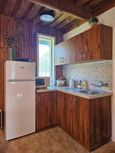 a kitchen with a white refrigerator and wooden cabinets at Šauklių pirtelė in Šaukliai