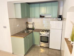a kitchen with green cabinets and a sink and a stove at Apartman Buccari in Bakar +8 photos