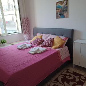 Una cama rosa con dos toallas encima. en B&B Appartamenti Napoli, en Nápoles