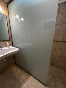 a bathroom with a glass shower door and a sink at JURAMA in Ciudad Lujan de Cuyo