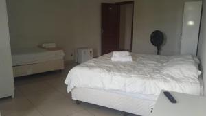 a bedroom with a large white bed and a desk at Hotel Santorine Prime - Itabira in Itabira