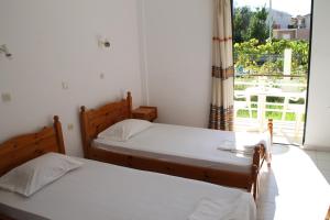 two beds in a room with a window at Kavos Central gardens in Kavos