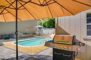 einen Grill mit Sonnenschirm neben einem Pool in der Unterkunft Modern Tims Ford Lake Home with Private Dock and Pool! in Lynchburg