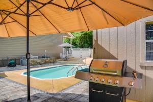 a barbecue grill with an umbrella next to a pool at Modern Tims Ford Lake Home with Private Dock and Pool! in Lynchburg