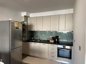 a kitchen with white cabinets and a stainless steel refrigerator at Hitech Appartment in Amaliás