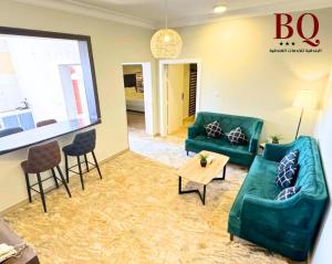 البندقية للخدمات الفندقية BQ HOTEL SUITES في بريدة: غرفة معيشة بها كنبتين خضراء وطاولة